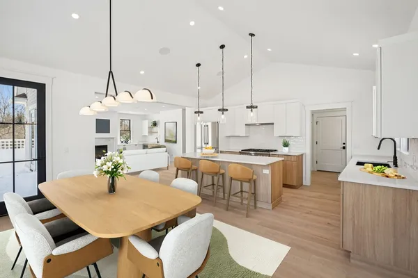 a kitchen with stainless steel appliances kitchen island granite countertop a table chairs and a view of living room