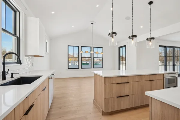 a large kitchen with kitchen island a large counter space a sink appliances and a window
