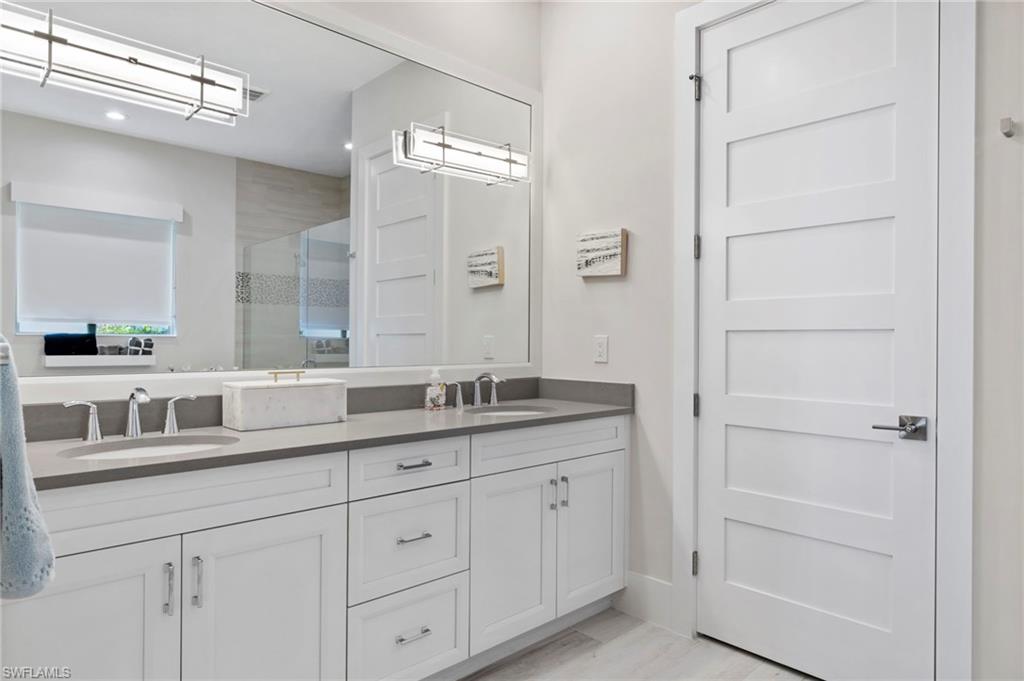 6136 Rodney Bay Lane Naples, FL 34113 - Photo 16 of 29 a bathroom with a granite countertop sink double and mirror