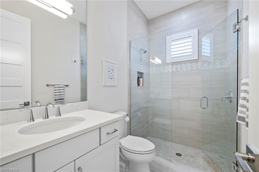 6136 Rodney Bay Lane Naples, FL 34113 - Photo 23 of 29 a bathroom with a sink toilet a mirror and shower