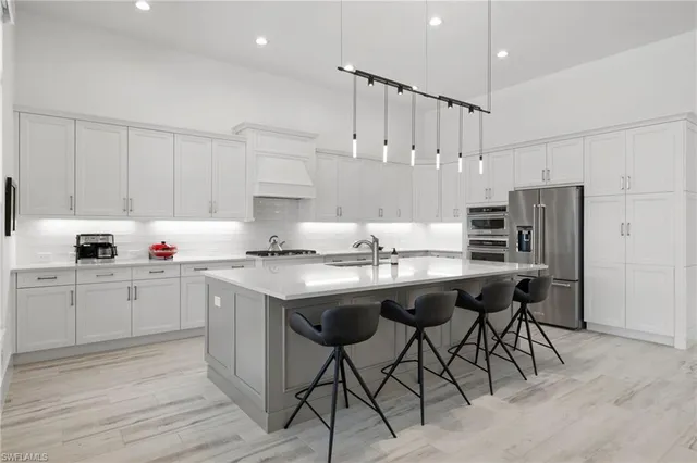 a kitchen with stainless steel appliances granite countertop a sink a stove a refrigerator and island with wooden floor