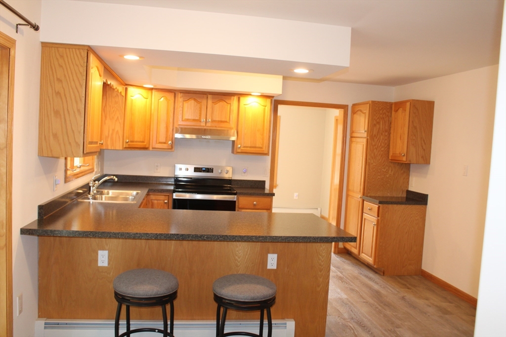 59 Strowbridge Road Northfield, MA 01360 - Photo 10 of 26 a kitchen with stainless steel appliances granite countertop a stove a sink a refrigerator white cabinets and wooden floor