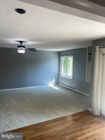 an empty room with wooden floor chandelier fan and windows