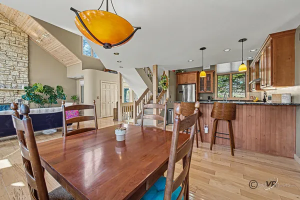 a open kitchen with stainless steel appliances granite countertop a stove top oven a dining table and chairs with wooden floor