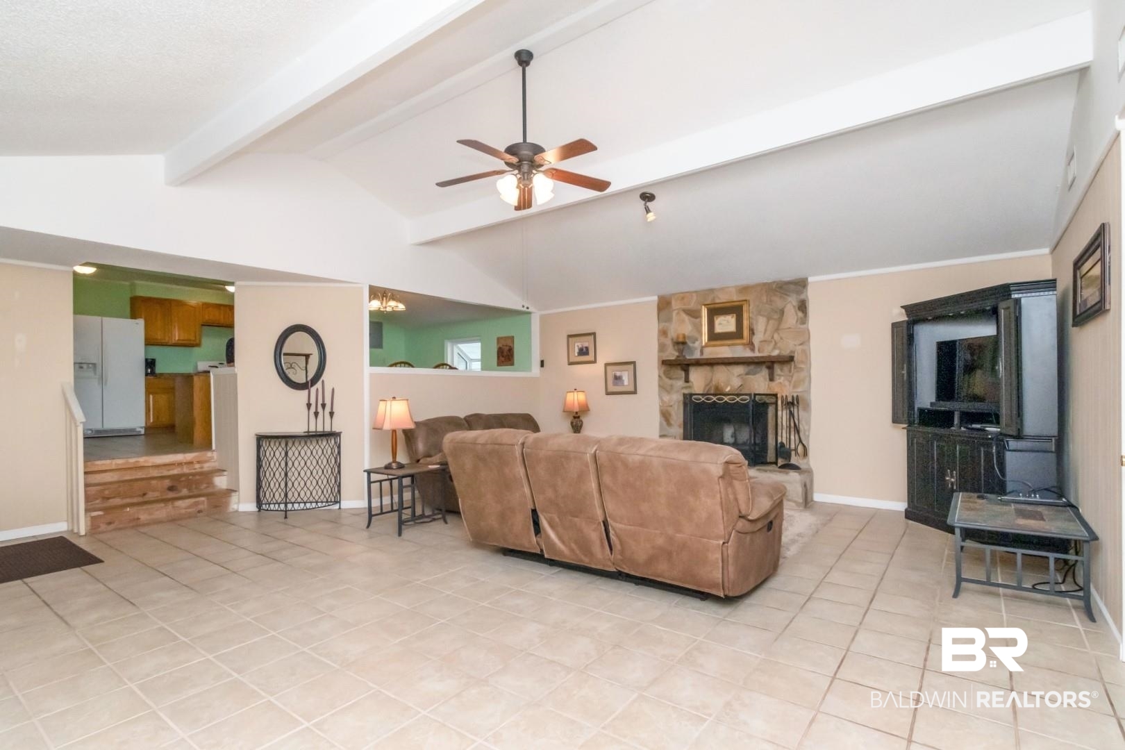 1321 Rainbow Drive West Mobile, AL 36693 - Photo 15 of 48 Living room featuring ceiling fan, lofted ceiling with beams, light tile patterned floors, and a stone fireplace