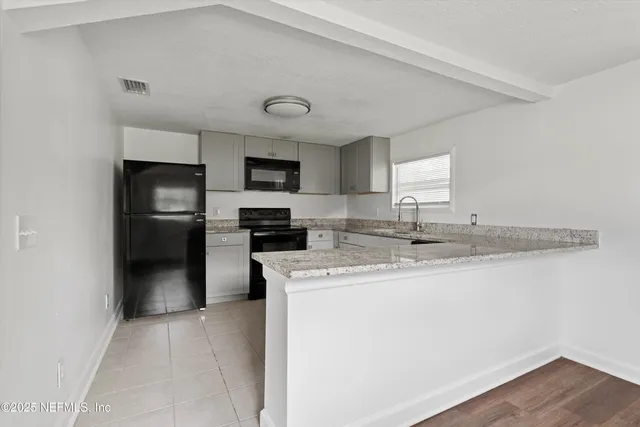 a kitchen with stainless steel appliances granite countertop a sink a stove a refrigerator a center island with wooden floor and cabinets