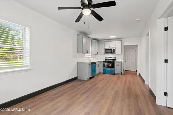 a view of empty room with wooden floor and fan