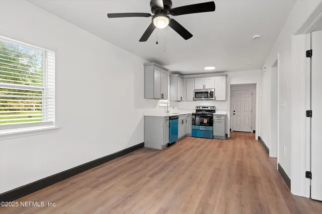 a kitchen with a refrigerator a stove and white cabinets