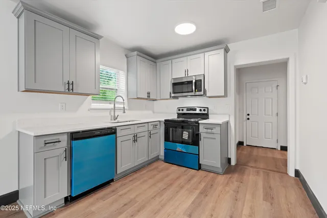 a kitchen with kitchen island granite countertop a sink cabinets and stainless steel appliances