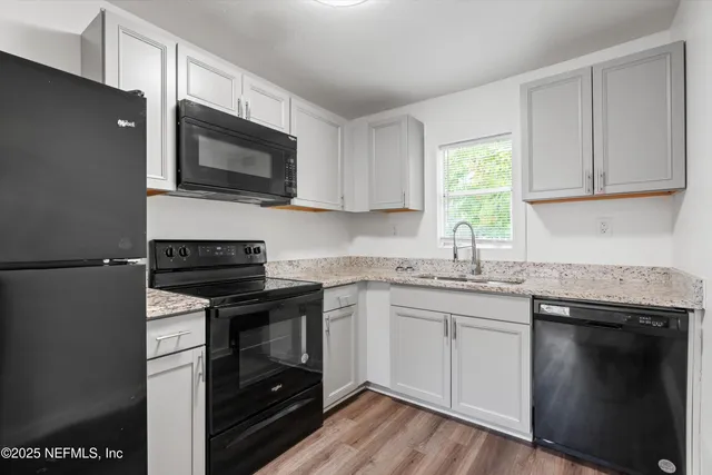 a kitchen with stainless steel appliances granite countertop white cabinets granite counter tops and a window