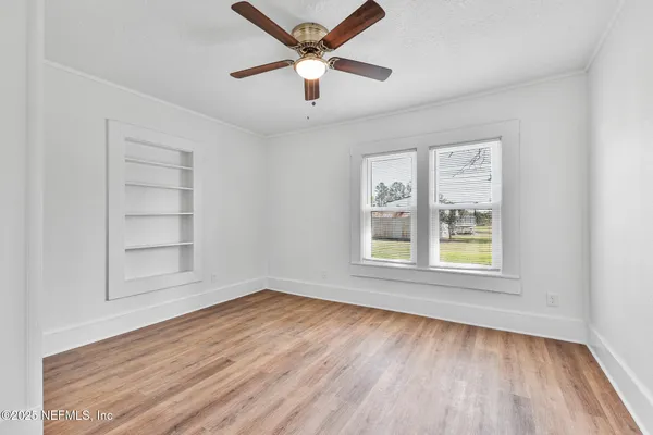 an empty room with wooden floor and windows