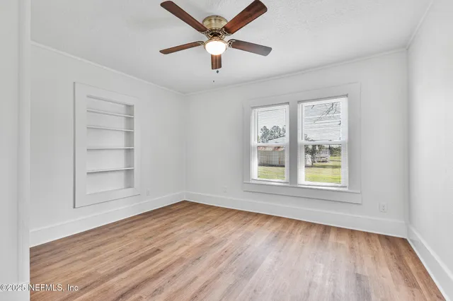 an empty room with wooden floor closet and windows