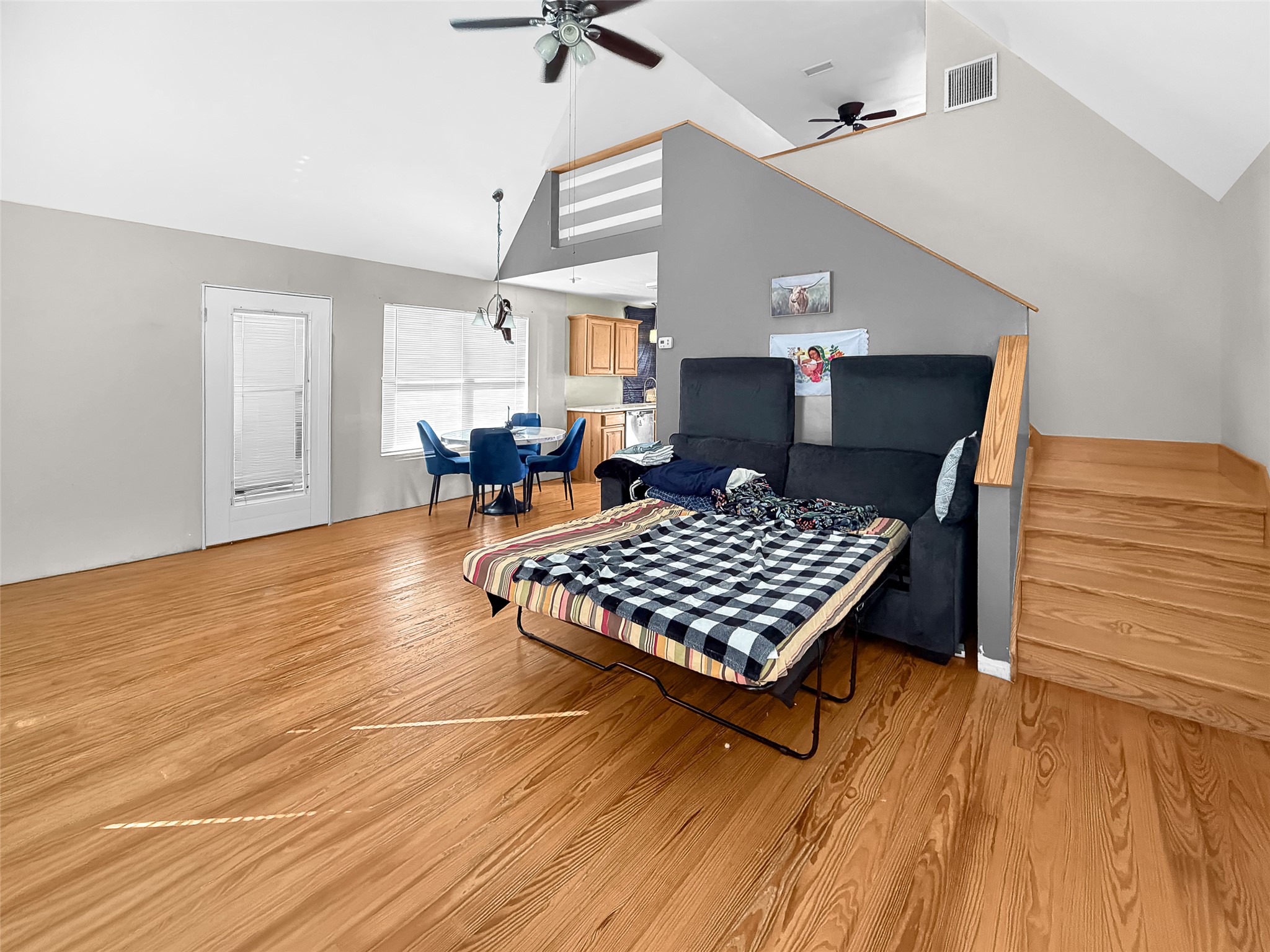 925 Long Hollow Road Dale, TX 78616 - Photo 10 of 26 Spacious open-concept living area featuring wood-finish flooring, vaulted ceilings, and a built-in staircase with wood railing