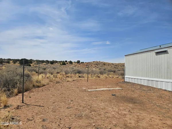 a view of a dry yard with wooden fence