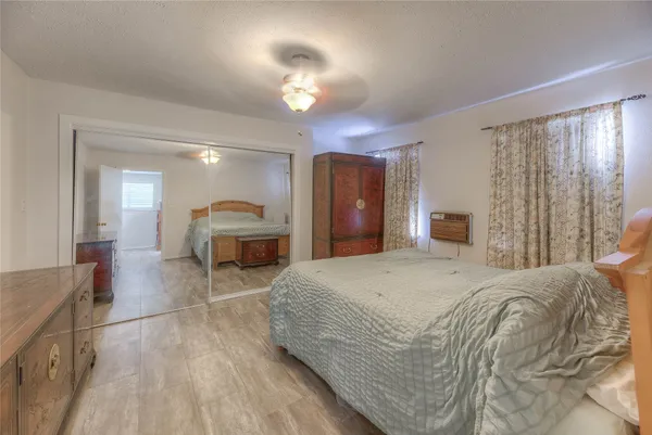 a spacious bedroom with a large bed a chandelier and dresser