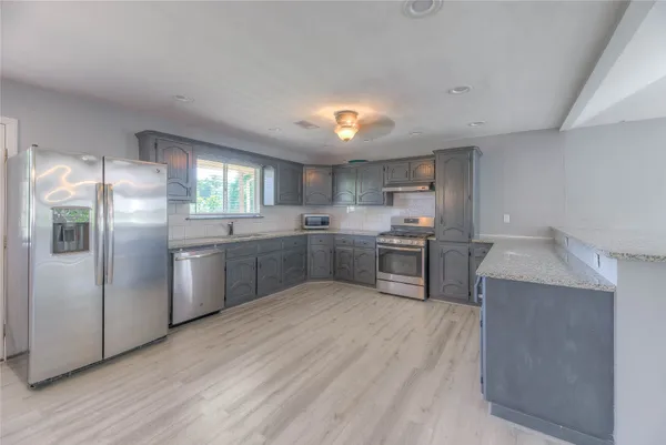 a kitchen with a sink a counter top space stainless steel appliances and cabinets