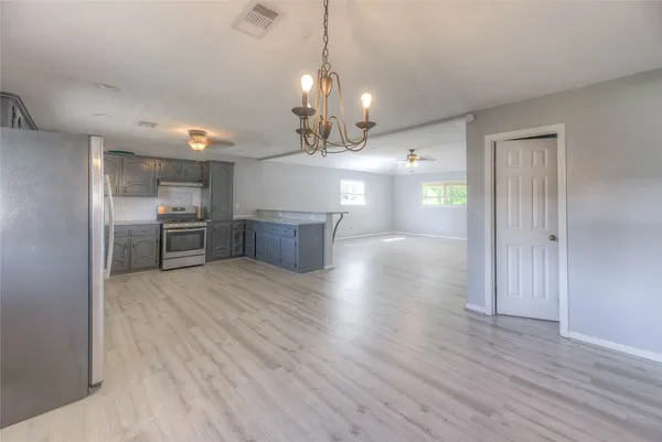 a view of a room with wooden floor kitchen and windows