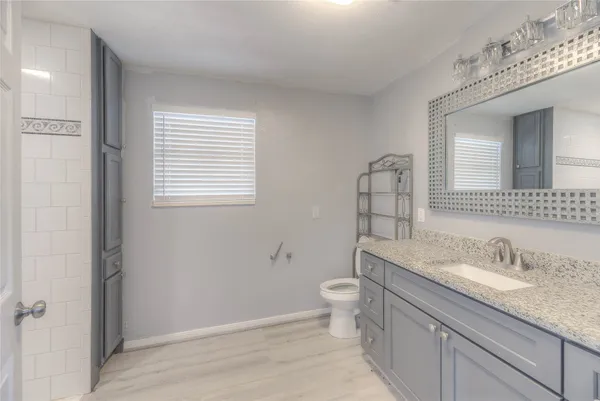 a bathroom with a granite countertop toilet a sink and a mirror