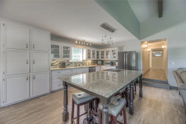 a kitchen with stainless steel appliances granite countertop a kitchen island a stove a table and chairs