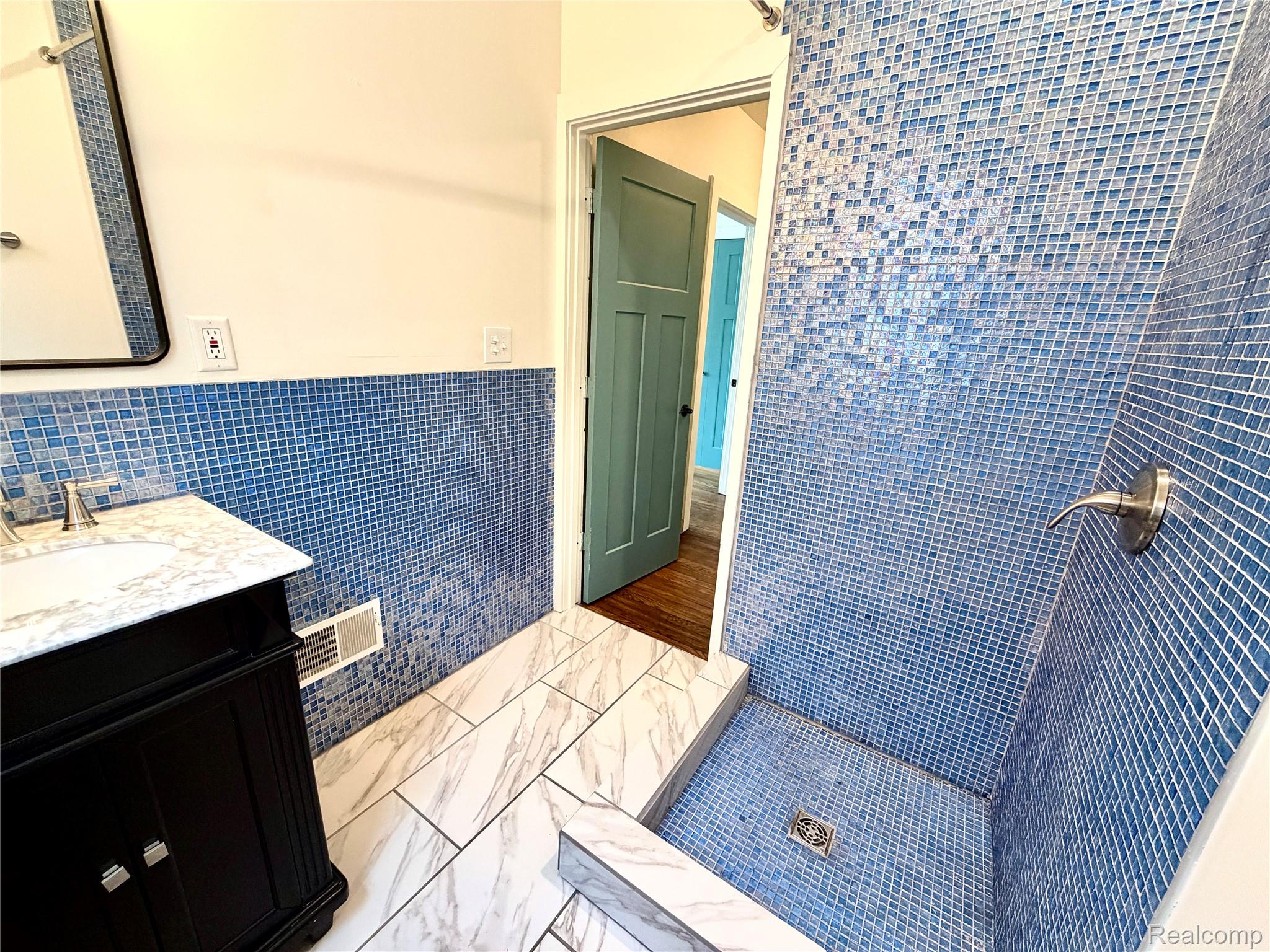 2045 Calvert Avenue Detroit, MI 48206 - Photo 26 of 41 Bathroom with tile walls, a shower stall, vanity, and wainscoting