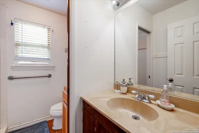 a bathroom with a granite countertop sink toilet and a mirror