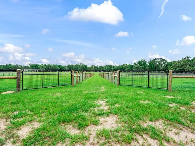 a view of a white house with a big yard and table and chairs with wooden fence