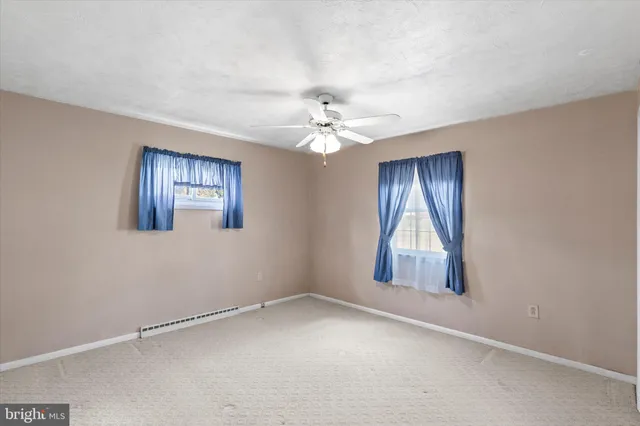 an empty room with windows and chandelier fan