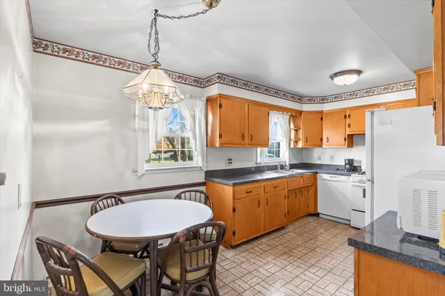 a kitchen with stainless steel appliances granite countertop a sink a stove a refrigerator with a dining table and chairs