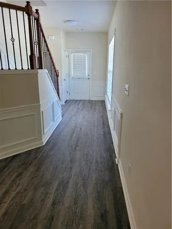 a view of a hallway with wooden floor and staircase