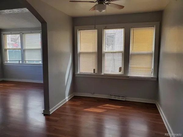 an empty room with wooden floor and windows