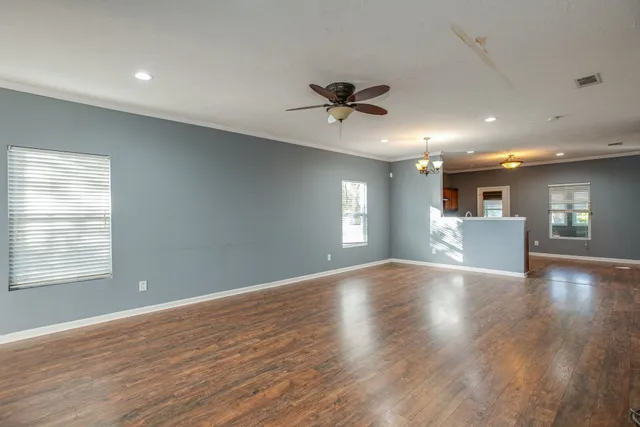a view of an empty room with a window and wooden floor