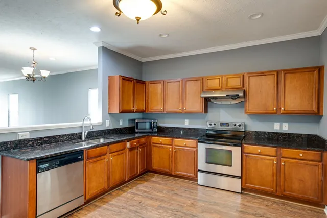 a kitchen with granite countertop stainless steel appliances a sink stove top oven and cabinets