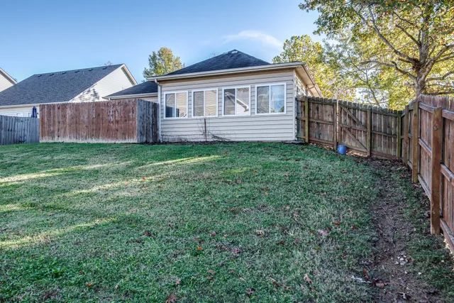 a view of a backyard with wooden fence and large trees