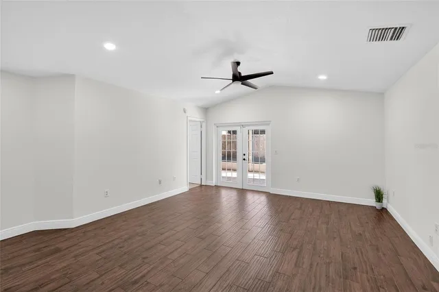 a view of an empty room with wooden floor and a ceiling fan