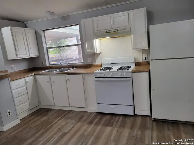 a kitchen with cabinets appliances and wooden floor