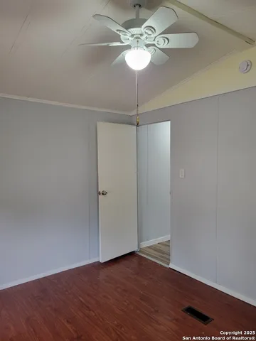 an empty room with wooden floor fan and window
