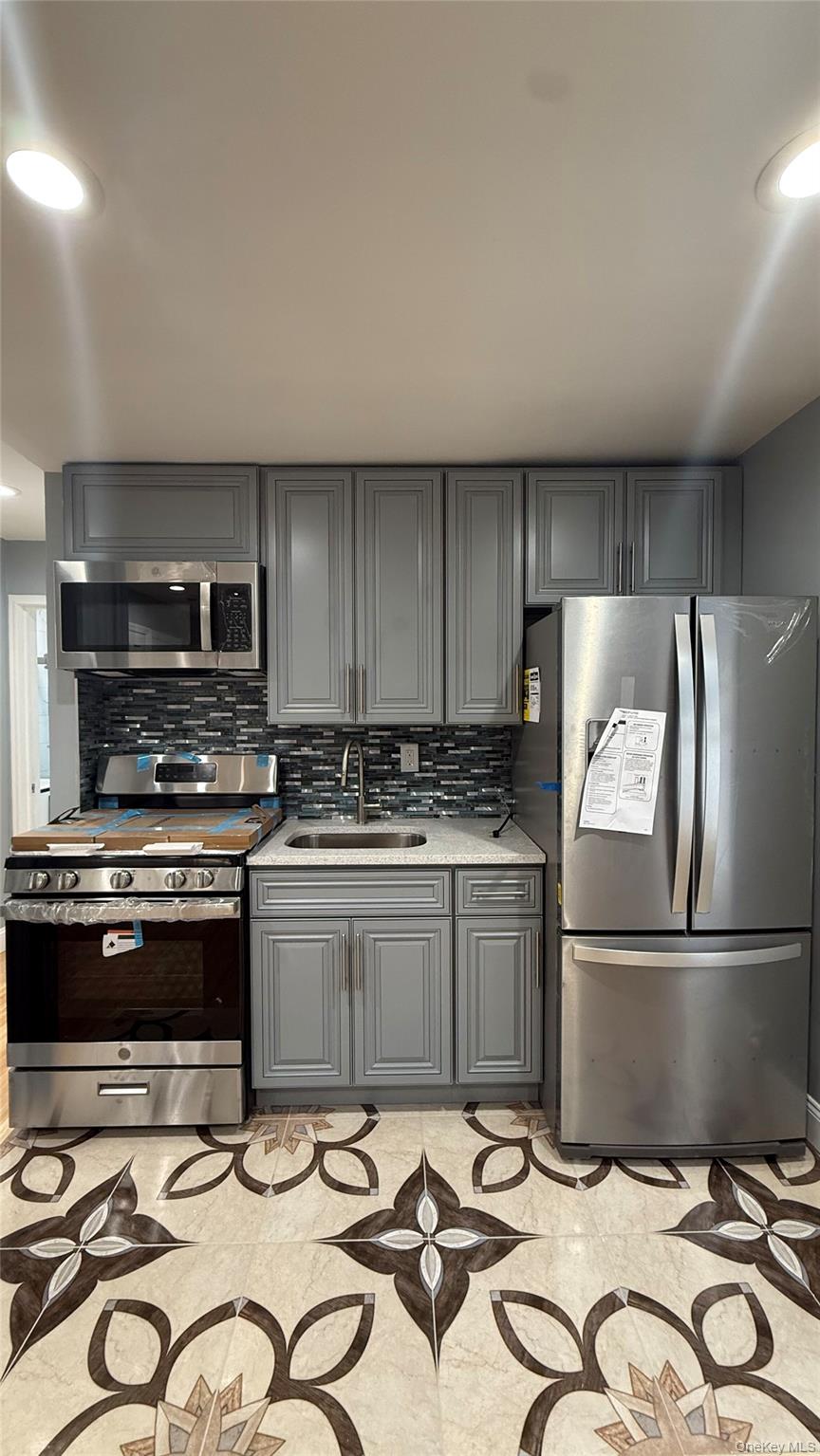 116-45 195th Street Queens, NY 11412 - Photo 15 of 21 a kitchen with kitchen island wooden cabinets and stainless steel appliances