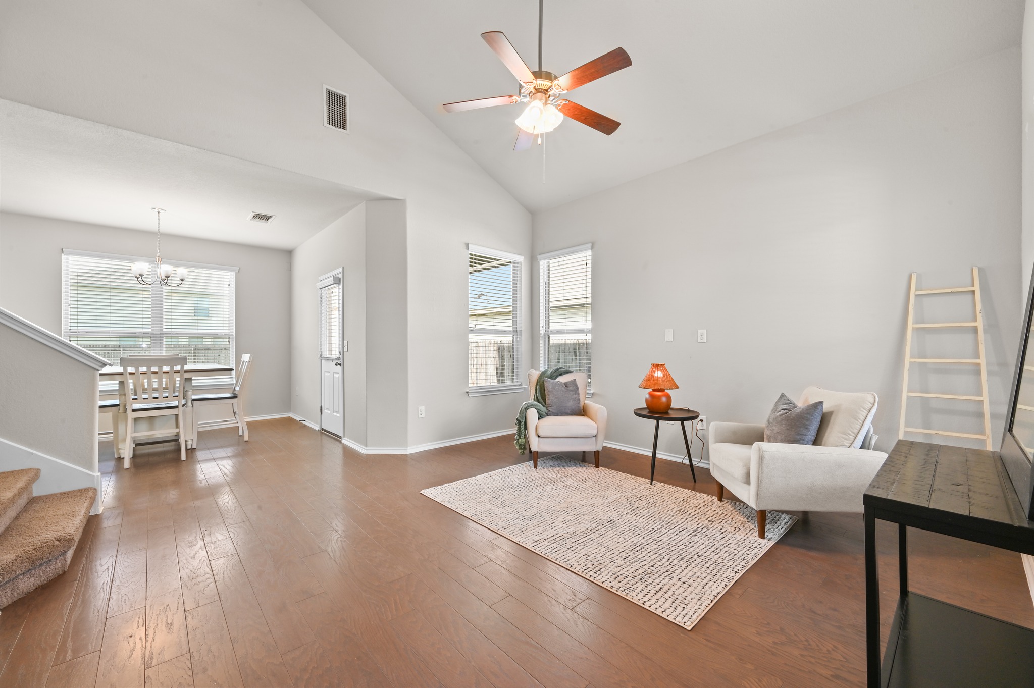 209 Noddy Road Buda, TX 78610 - Photo 4 of 30 Vaulted ceiling in living area featuring wood-finish flooring, a ceiling fan, and large windows with blinds