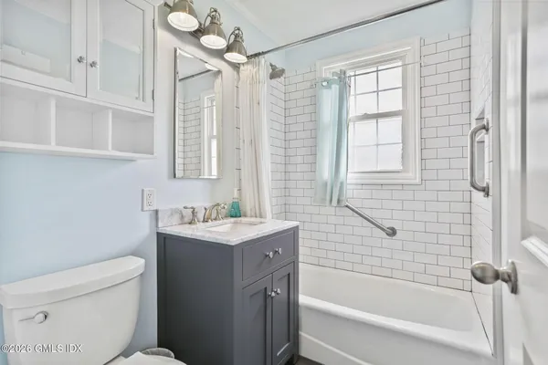 a bathroom with a granite countertop sink a toilet and shower