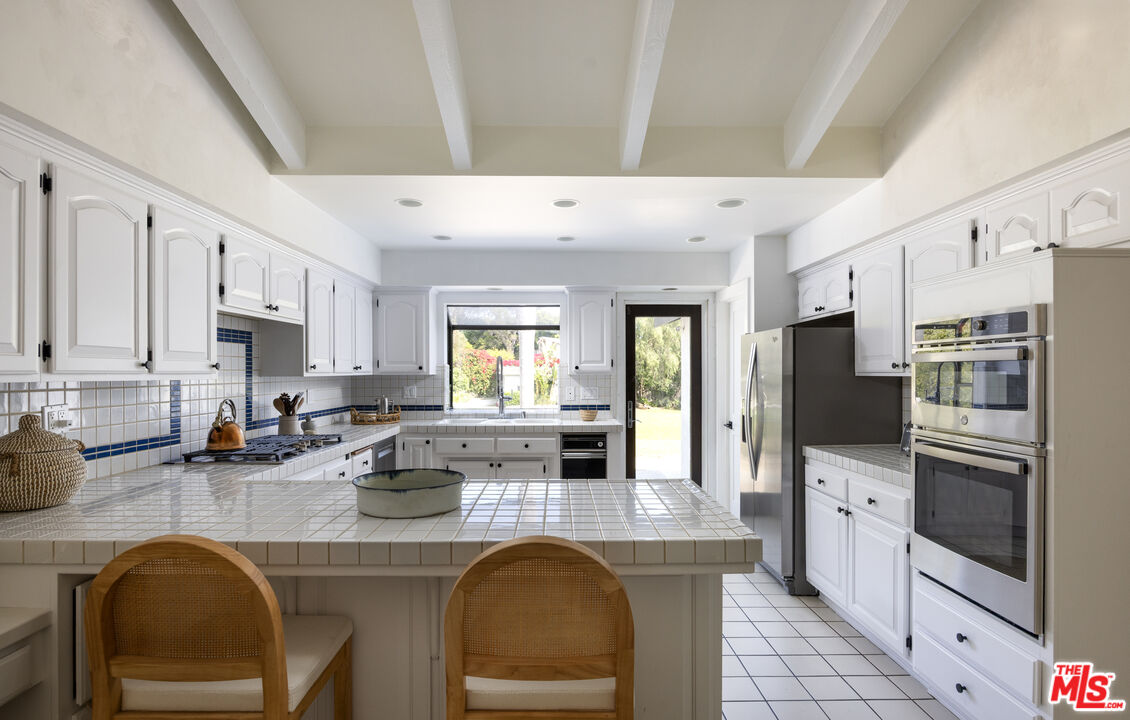 29328 Heathercliff Road Malibu, CA 90265 - Photo 13 of 41 a kitchen with stainless steel appliances granite countertop a sink a stove refrigerator and cabinets