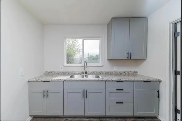 a kitchen with granite countertop white cabinets and a sink