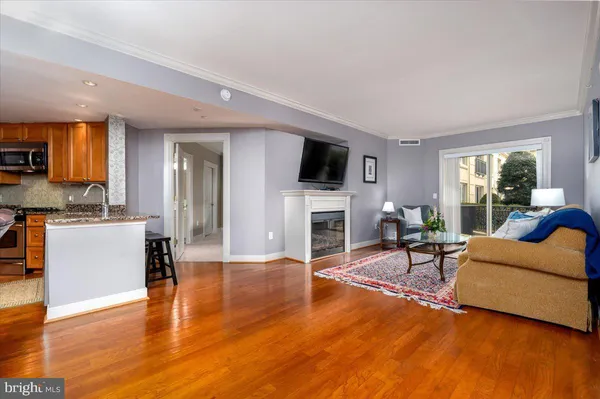 a living room with furniture a fireplace a flat screen tv and kitchen view