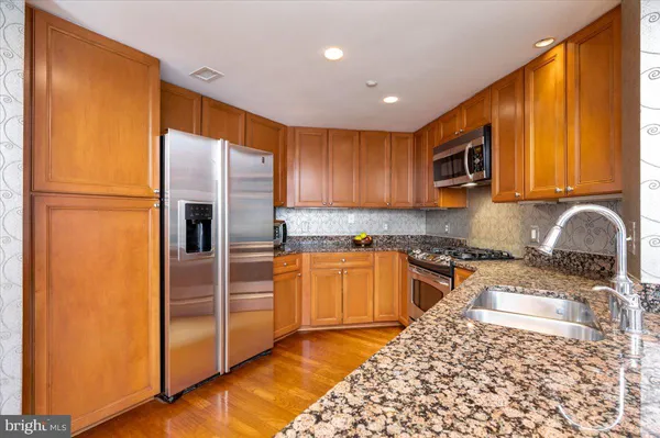a kitchen with stainless steel appliances granite countertop a refrigerator and a stove top oven