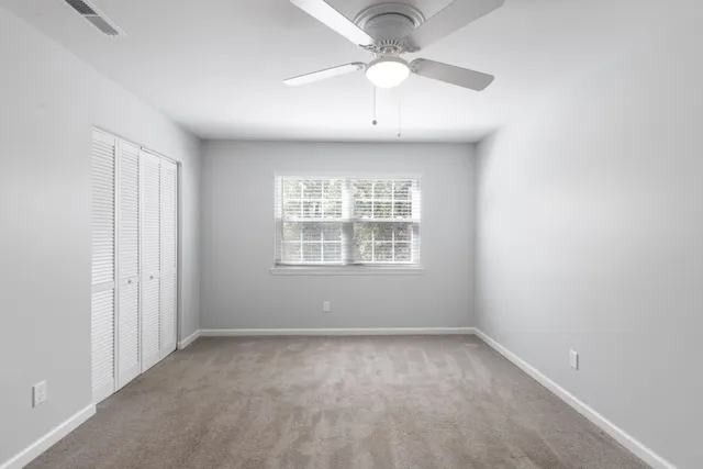an empty room with a window and a fan