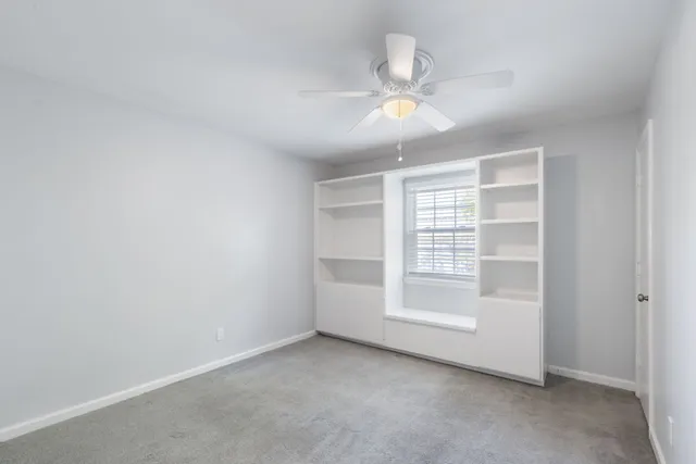 an empty room with a ceiling fan and a window