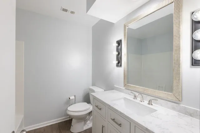 a bathroom with a granite countertop toilet a sink and a mirror