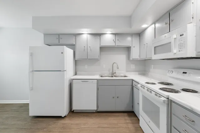 a kitchen with a sink a refrigerator and white cabinets