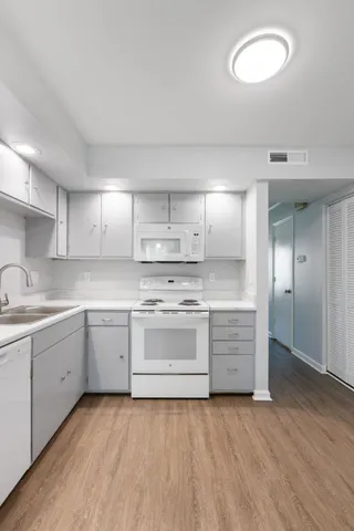 a large white kitchen with a sink dishwasher stove and cabinets