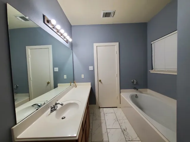 a bathroom with a tub sink and mirror