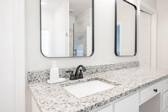 a bathroom with a granite countertop sink and a mirror